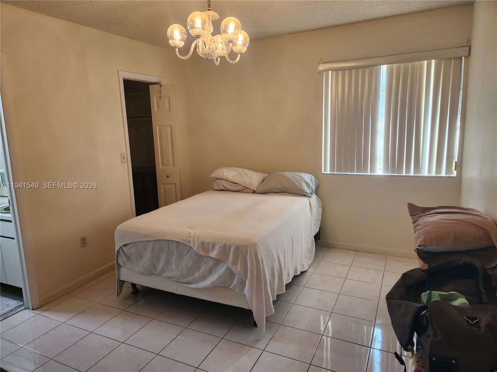 8990 Southwest 24th Street, Unit 228 Miami, FL 33165 - Photo 7 of 17 a bedroom with a bed and a chandelier