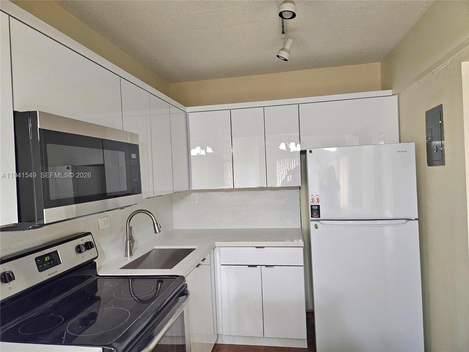 8990 Southwest 24th Street, Unit 228 Miami, FL 33165 - Photo 7 of 20 a kitchen with stainless steel appliances granite countertop a refrigerator a stove a sink and a microwave