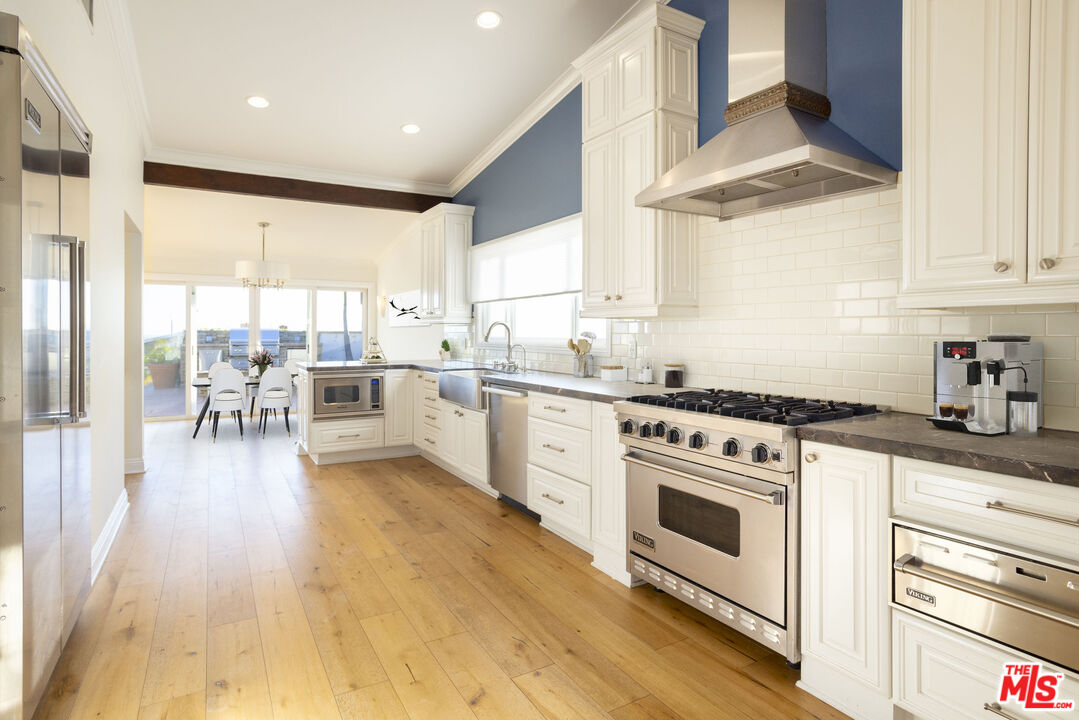 18436 Wakecrest Drive Malibu, CA 90265 - Photo 10 of 41 a kitchen with a stove a sink and white cabinets with wooden floor
