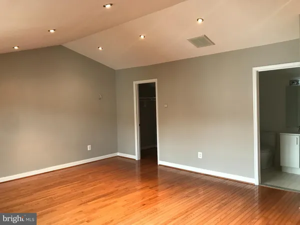 an empty room with wooden floor and entrance