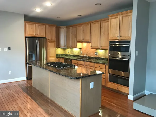 a kitchen with kitchen island granite countertop a refrigerator and a stove
