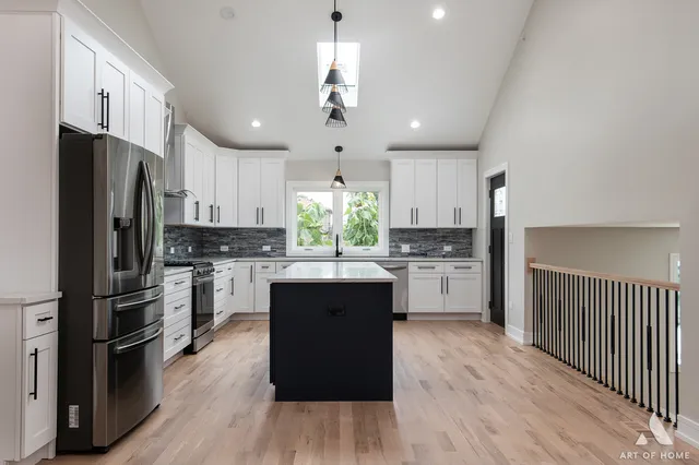 a kitchen with stainless steel appliances a refrigerator a sink dishwasher a stove and white cabinets with wooden floor