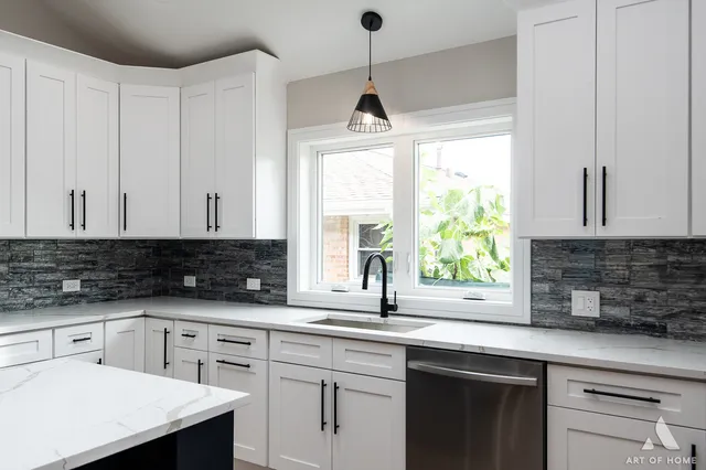 a kitchen with granite countertop a sink white cabinets and a window