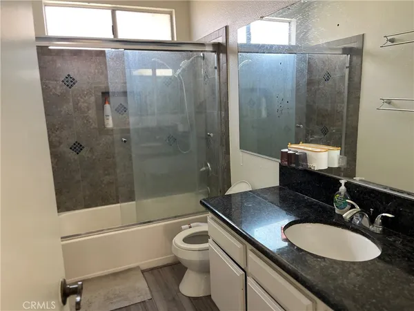 a bathroom with a granite countertop sink toilet a mirror and shower