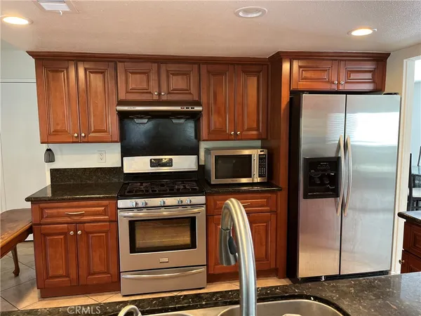 a kitchen with granite countertop a refrigerator stove and microwave