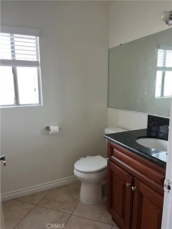 a bathroom with a granite countertop toilet a sink and a window