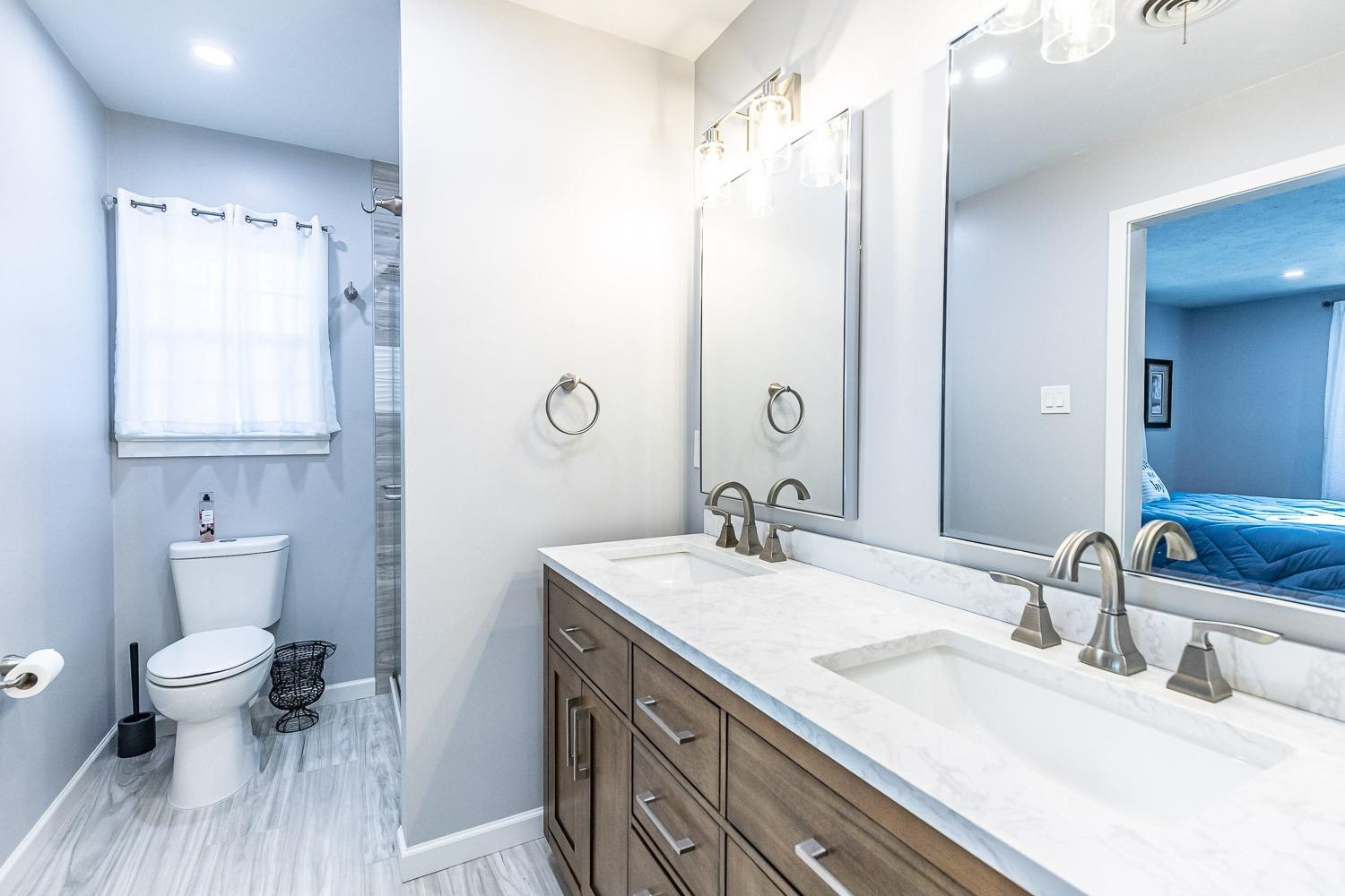 3417 61st Street Lubbock, TX 79413 - Photo 22 of 39 a bathroom with a granite countertop sink a toilet and a mirror