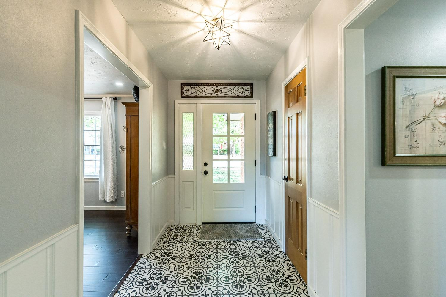 3417 61st Street Lubbock, TX 79413 - Photo 3 of 39 a view of a hallway with wooden floor and a chandelier