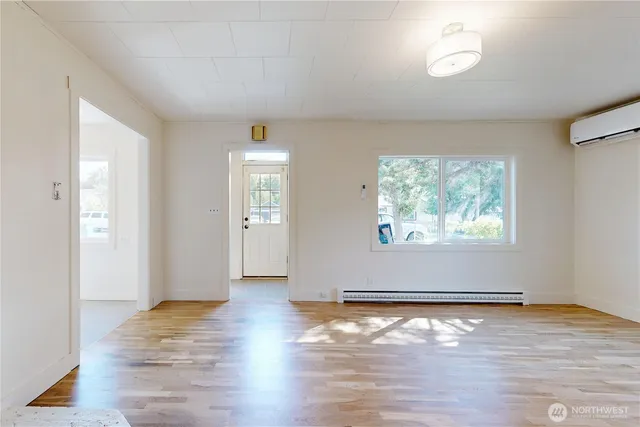 an empty room with wooden floor and window