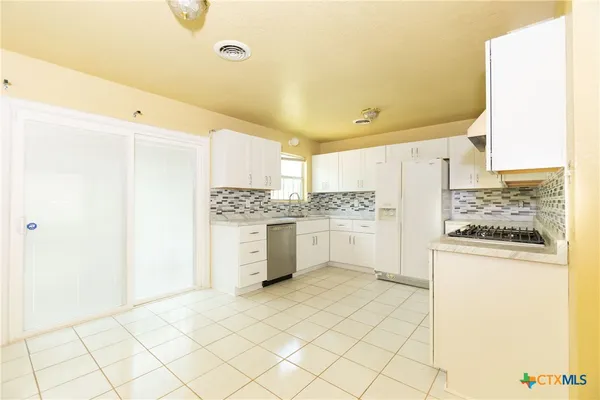 a kitchen with a refrigerator and white cabinets