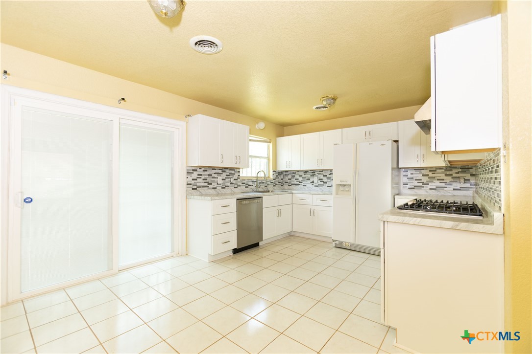 a kitchen with a refrigerator and white cabinets