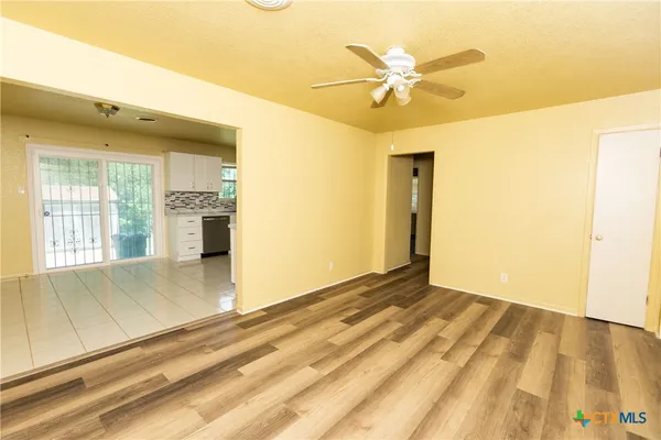 a view of an empty room with window and a ceiling fan