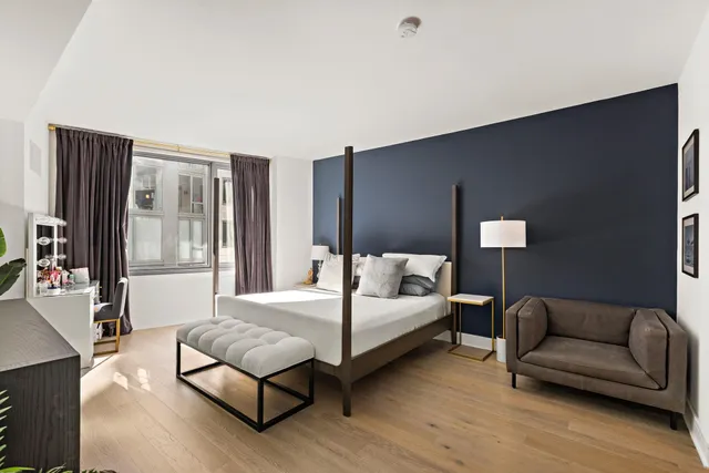 a bedroom with a bed couch and wooden floor