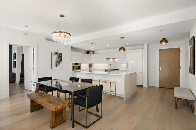 a kitchen with stainless steel appliances kitchen island granite countertop a table chairs and a refrigerator