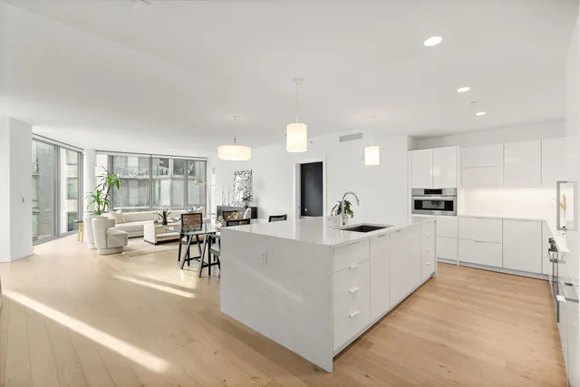 a large white kitchen with kitchen island a sink a stove a dining table and chairs