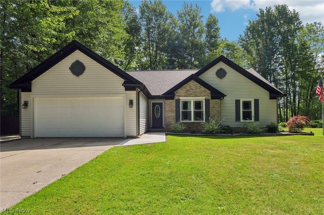 Ranch-style exterior featuring light-colored siding, a dark roof, and a two-car garage