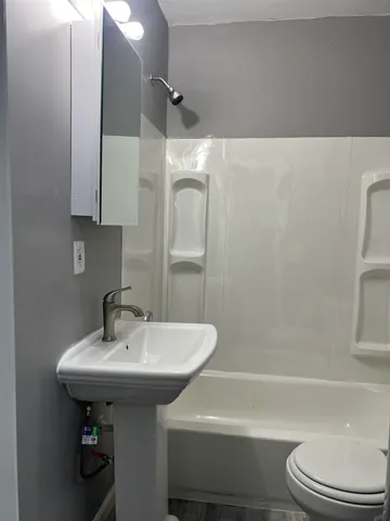 a bathroom with a sink a toilet and shower