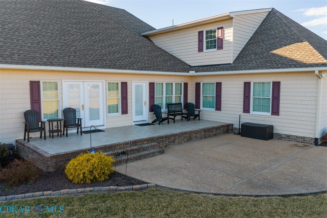 Rear view of house with a patio and a shingled roof