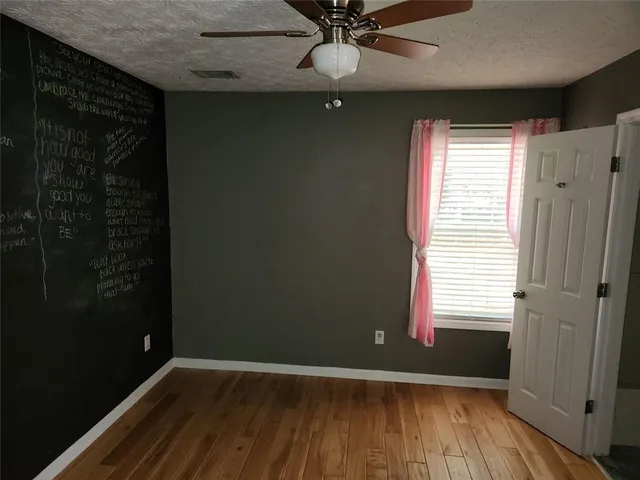 a view of an empty room with wooden floor and a fireplace