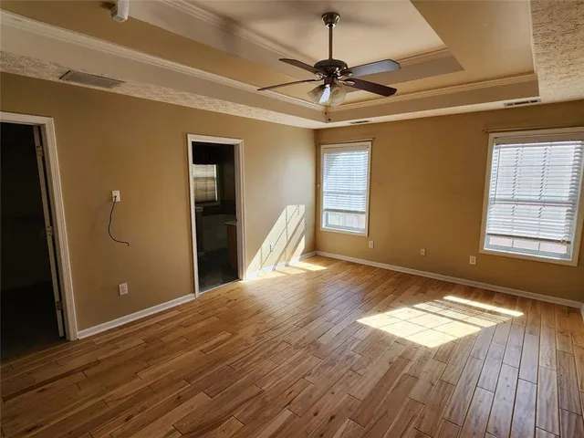 a view of an empty room with wooden floor ceiling fan and a window