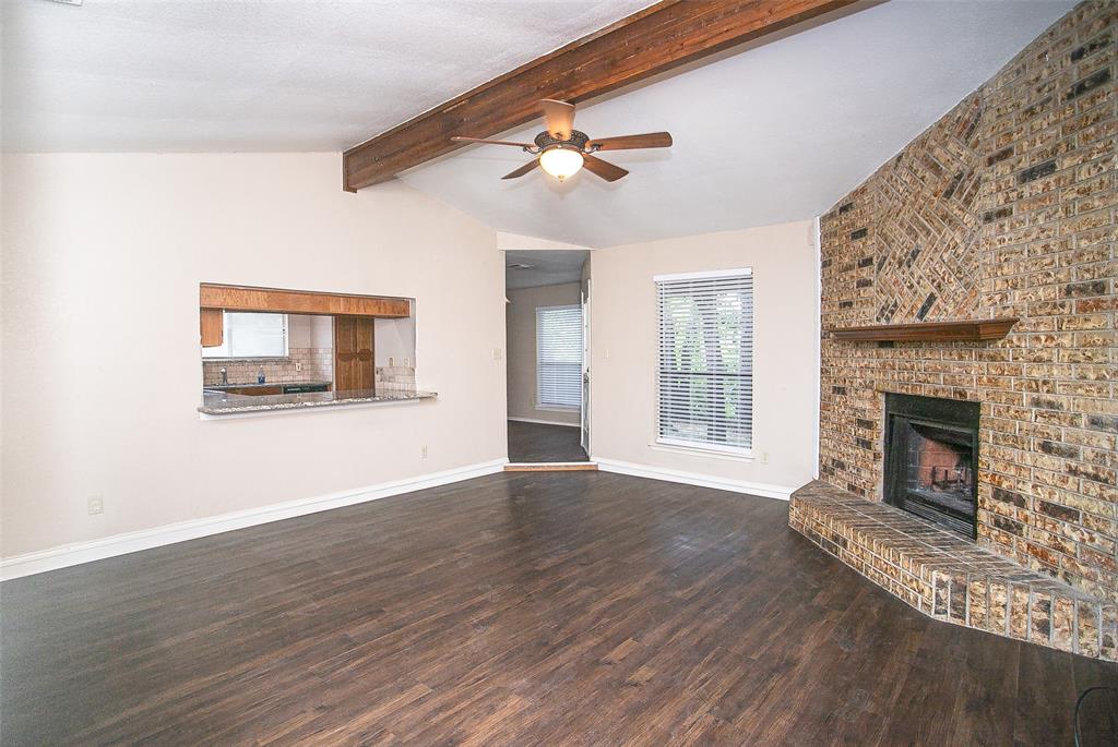 2019 West Nathan Lowe Road Arlington, TX 76017 - Photo 4 of 21 Living area featuring a brick fireplace with a wood mantel, wood-finish flooring, and a ceiling fan