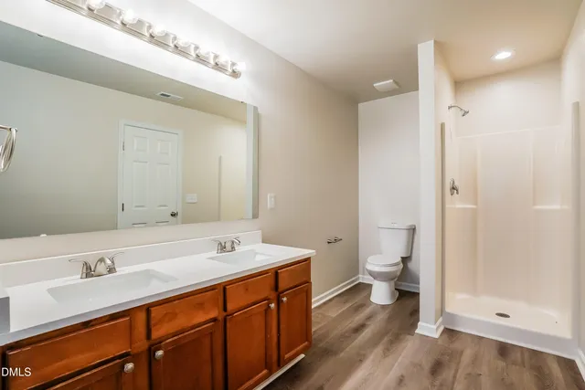 a spacious bathroom with a double vanity sink a mirror and a toilet