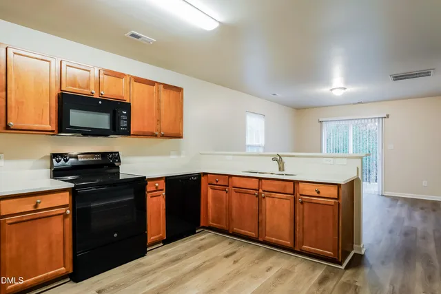 a kitchen with stainless steel appliances granite countertop wooden cabinets a stove a sink and a microwave