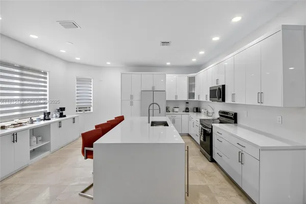 a large white kitchen with lots of counter space sink and appliances