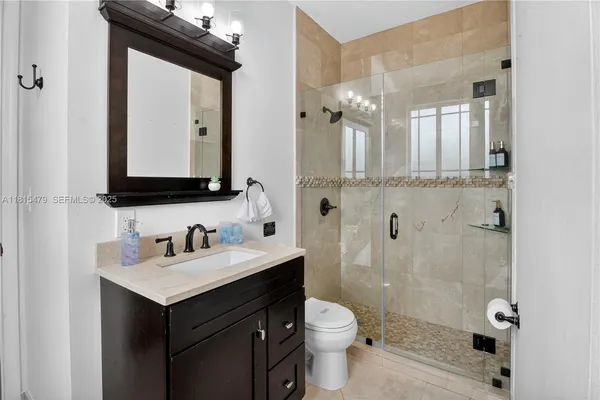 a bathroom with a double vanity sink toilet mirror and shower