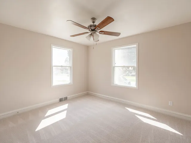 an empty room with windows and fan