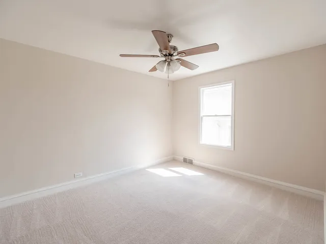 an empty room with a window and a fan