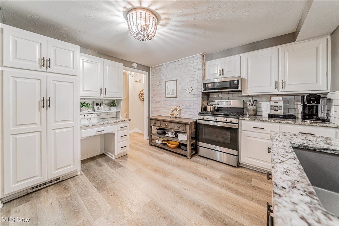 595 Moorfield Road Fairlawn, OH 44313 - Photo 12 of 50 Kitchen featuring decorative backsplash, stainless steel appliances, white cabinets, and light wood finished floors