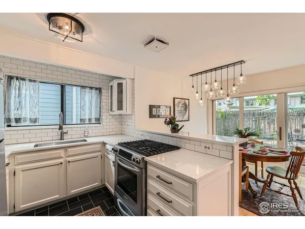 a kitchen that has a sink a stove a table and chairs in it