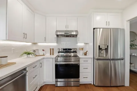 a kitchen with white cabinets and sink