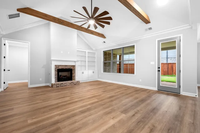 an empty room with windows fireplace and wooden floor