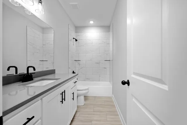 a bathroom with a granite countertop sink a toilet and shower
