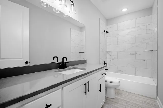 a bathroom with a granite countertop sink a toilet and bathtub