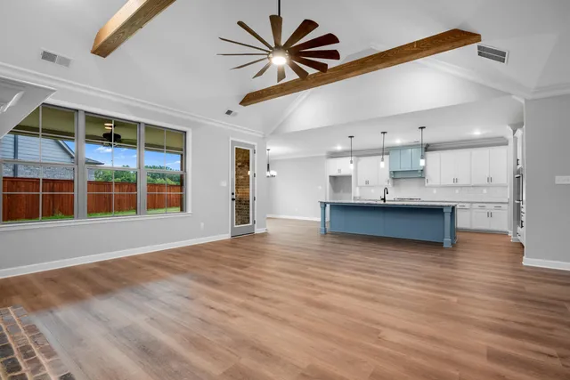 a view of an empty room with a window and kitchen view