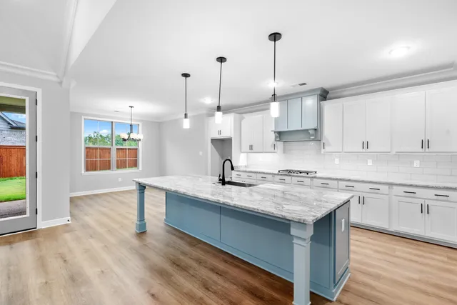 a kitchen with kitchen island granite countertop a sink stove and wooden floor