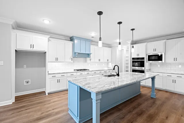 a kitchen with stainless steel appliances granite countertop a sink a stove a refrigerator and white cabinets