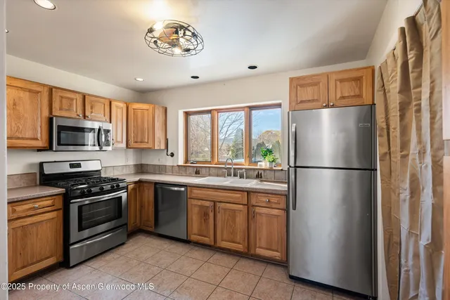 a kitchen with stainless steel appliances granite countertop a refrigerator a sink a stove a microwave and island
