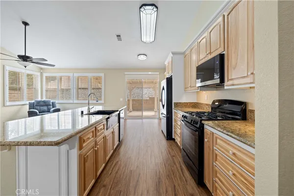 a kitchen with stainless steel appliances granite countertop a stove top oven a sink a dining table and chairs with wooden floor