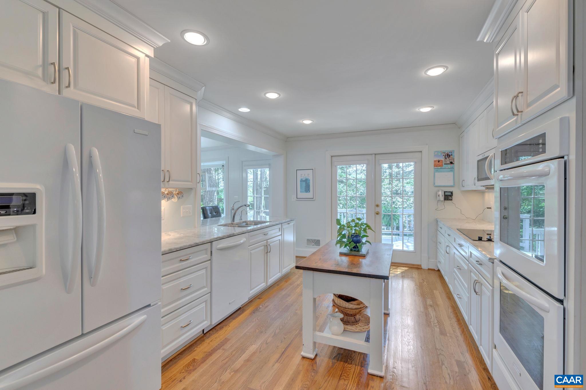 1440 Grove Road Charlottesville, VA 22901 - Photo 18 of 72 a large kitchen with stainless steel appliances a large counter top a stove a refrigerator cabinets and living room view