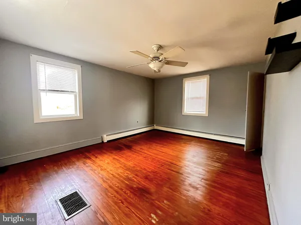 an empty room with wooden floor chandelier fan and windows