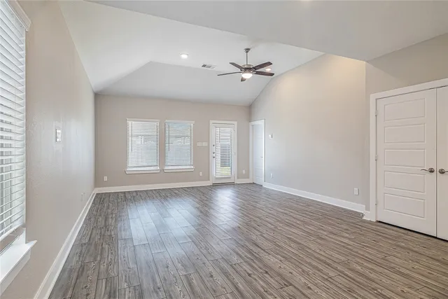an empty room with wooden floor window and ceiling fan