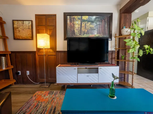 a living room with furniture a flat screen tv and a floor to ceiling window