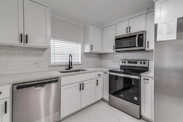 a kitchen with white cabinets and stainless steel appliances