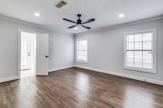 an empty room with wooden floor and a ceiling fan