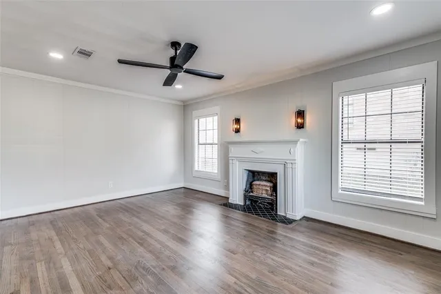 a view of an empty room with wooden floor fireplace and a window