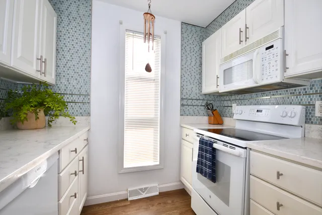 a kitchen with granite countertop white cabinets and white appliances